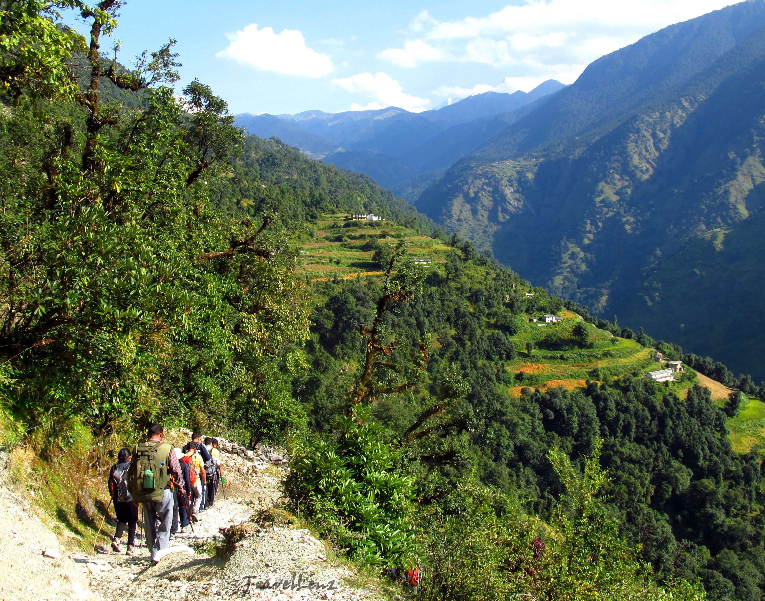 Trekkers walking through the countryside with mountains and terrace fields in the backdrop