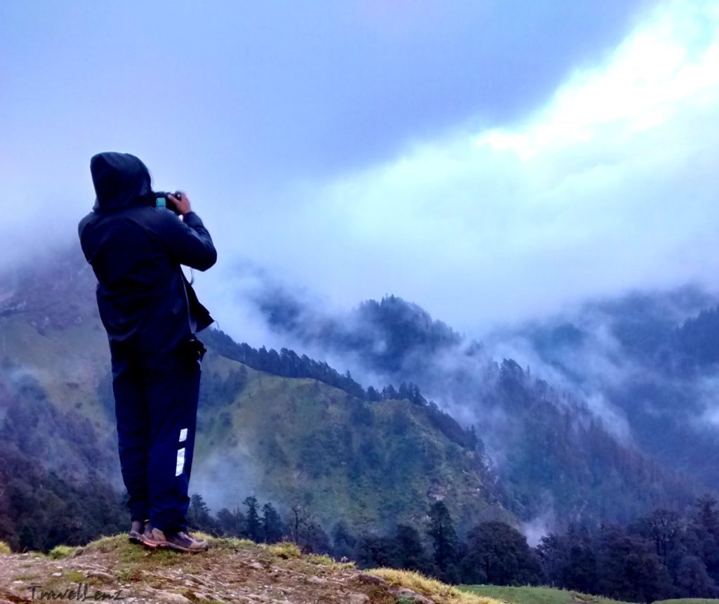 A trekker taking a photo of a misty mountain valley