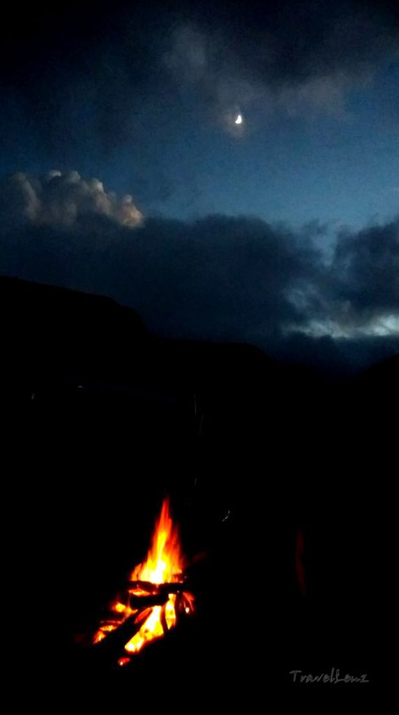 A campfire set against a moonlit night