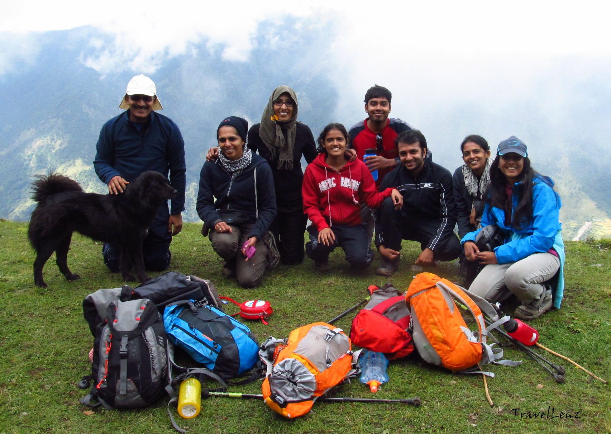 Trekkers posing on a grassland with a dog