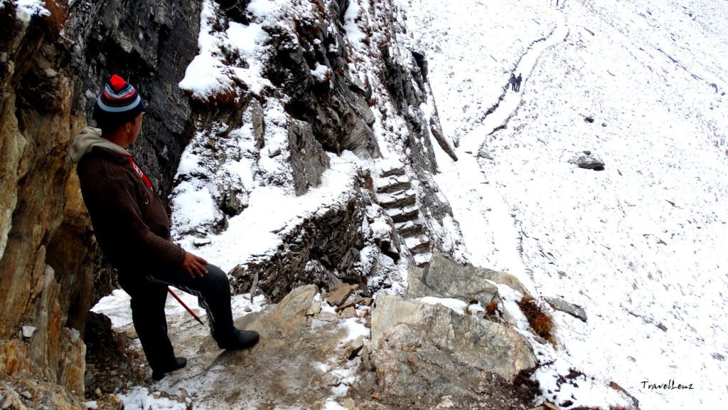 A trekker waits at top of a flight of stone steps cut into the rocky mountain on the way to Roopkund summit