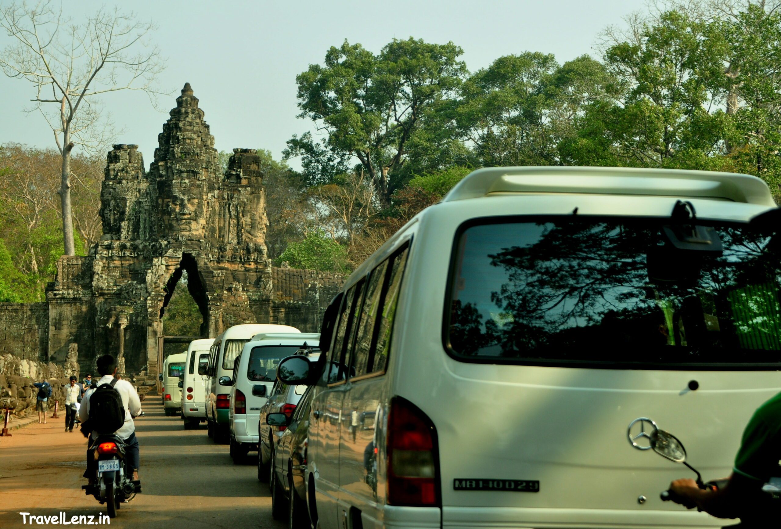 Vehicles line up to enter the south gate tower of Angkor Thom