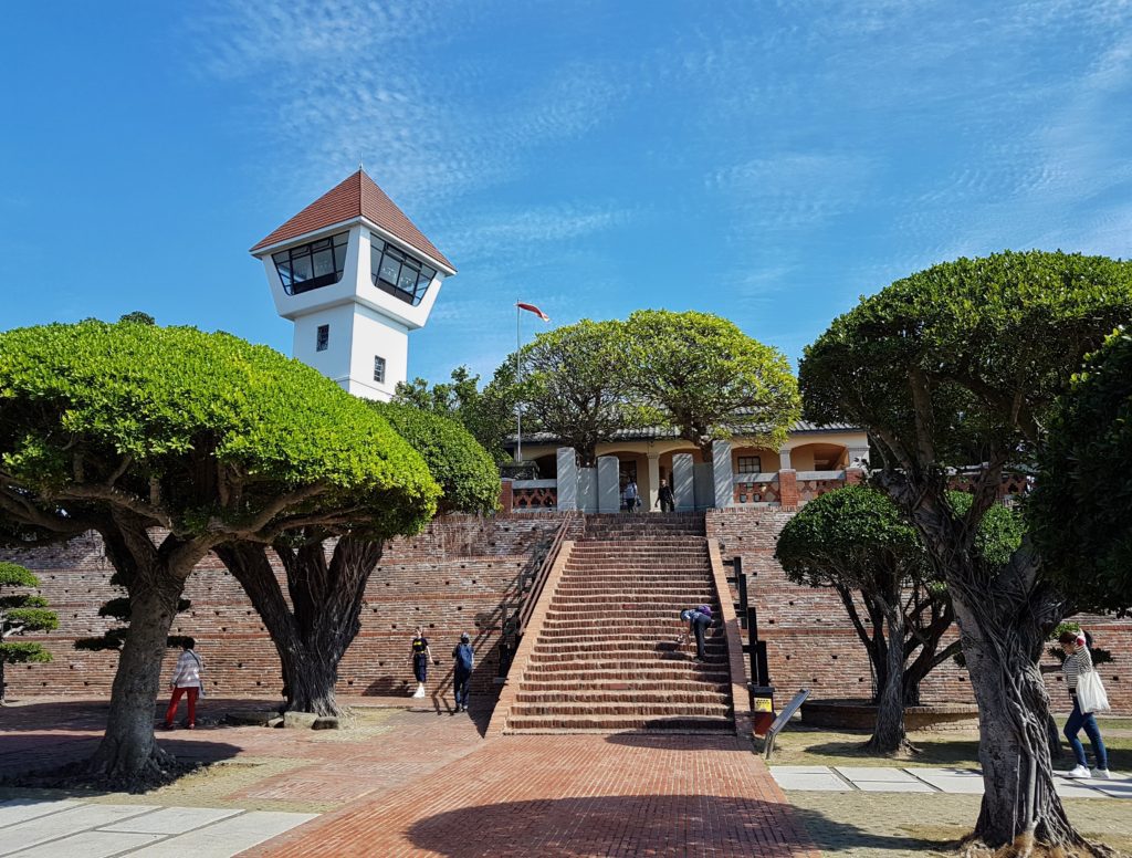 A stairway leads to an observation tower with trees around under a blue sky