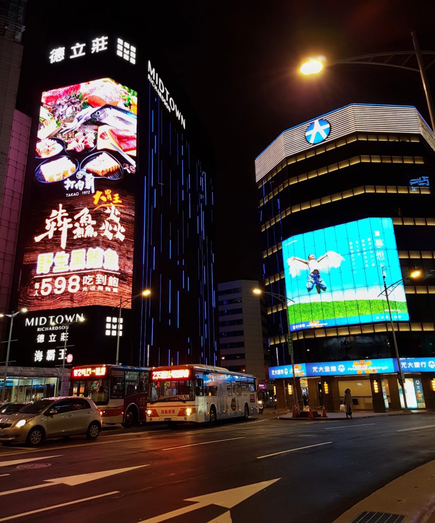 Street scene in Taipei with neon lit buildings and traffic