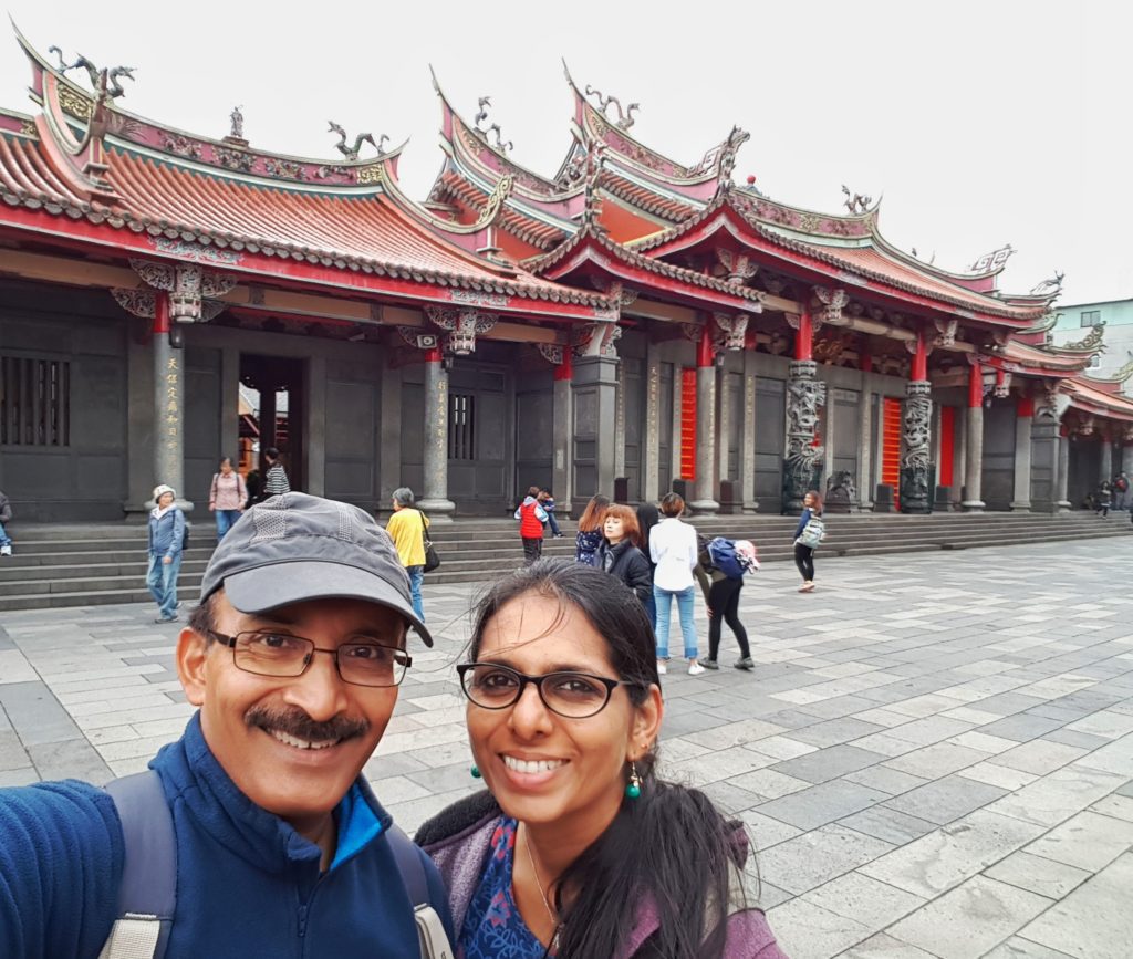 A couple posing in front of a Buddhist temple