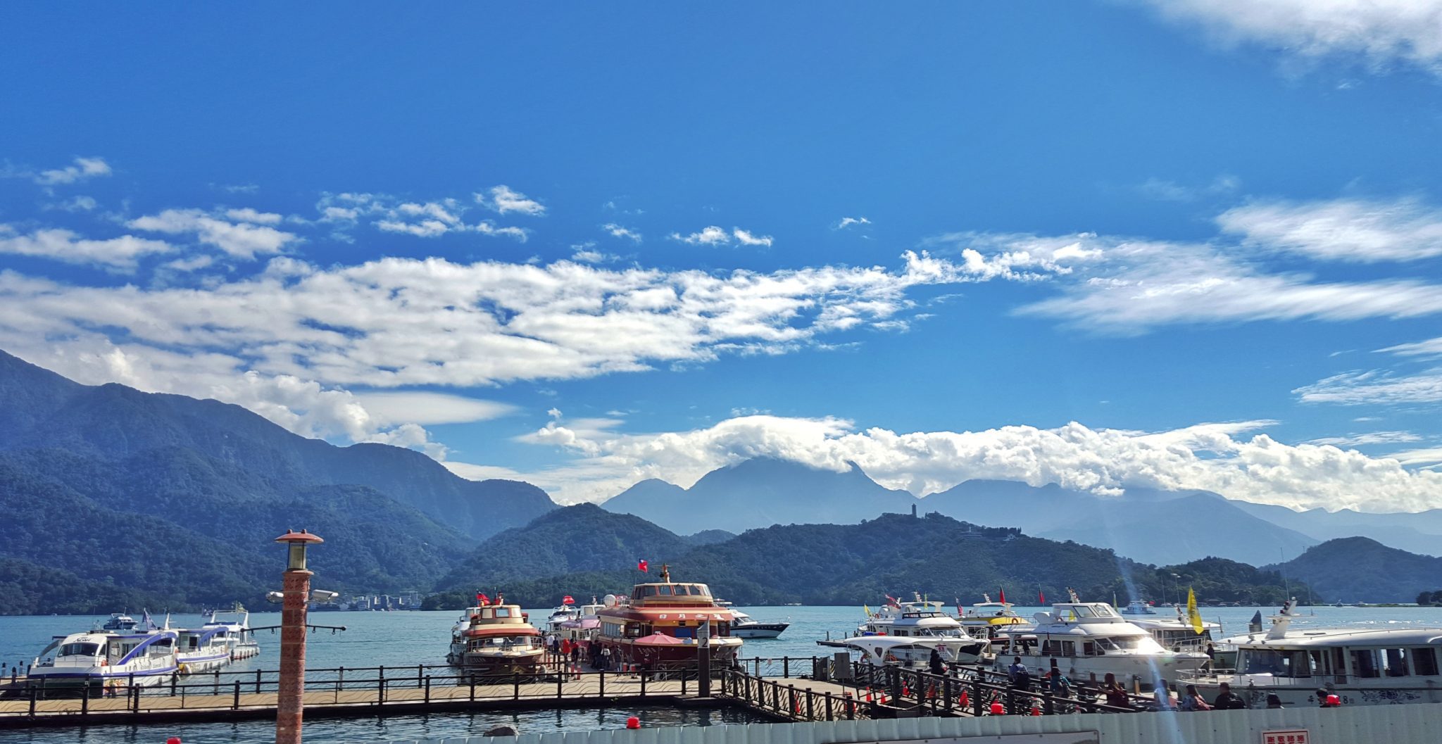 Clouds in a blue sky over a lake surrounded by mountains