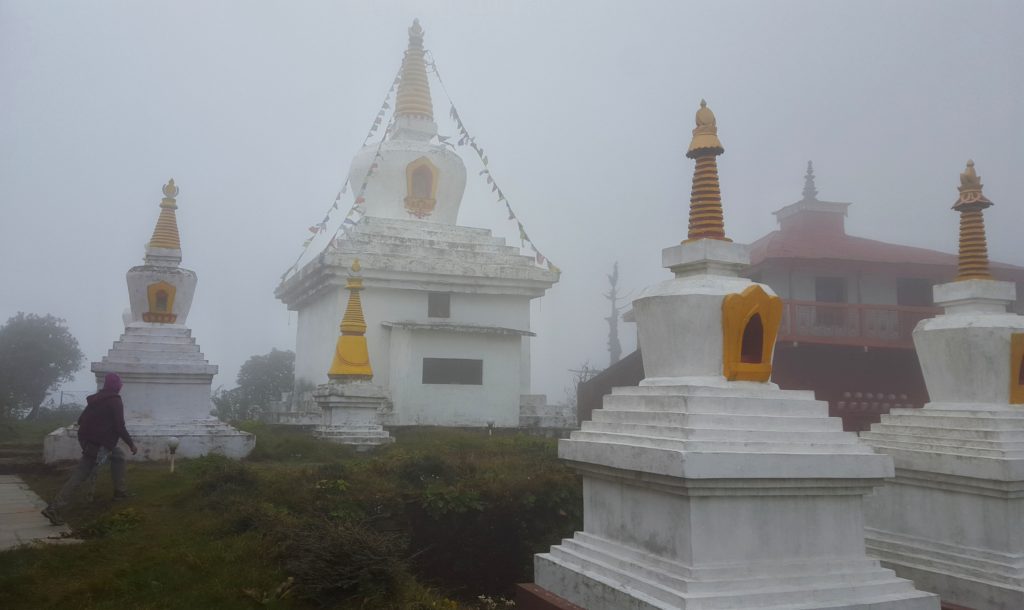 White chortens with yellow steeples set against mist
