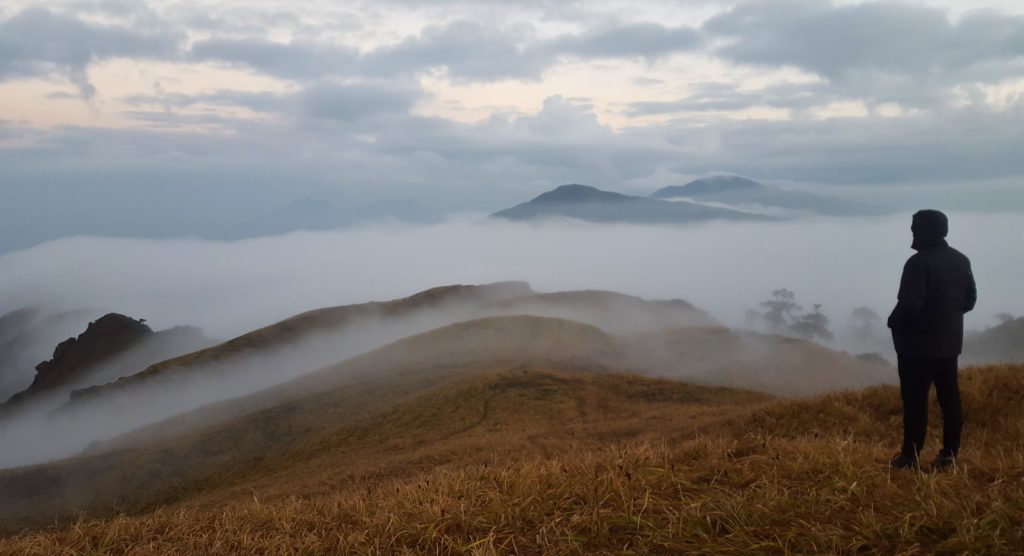 A man looking over a sea of clouds rising over the mountains