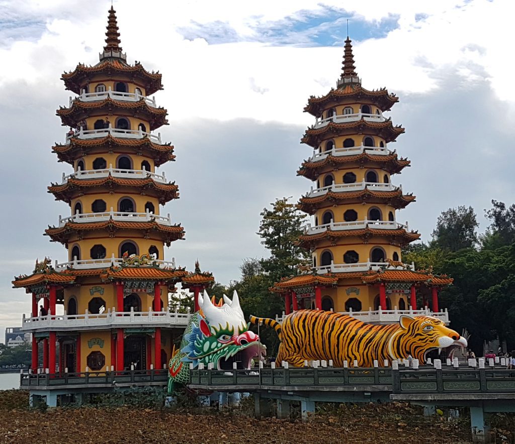 Two multi tiered pagodas with statues of a dragon and tiger in front