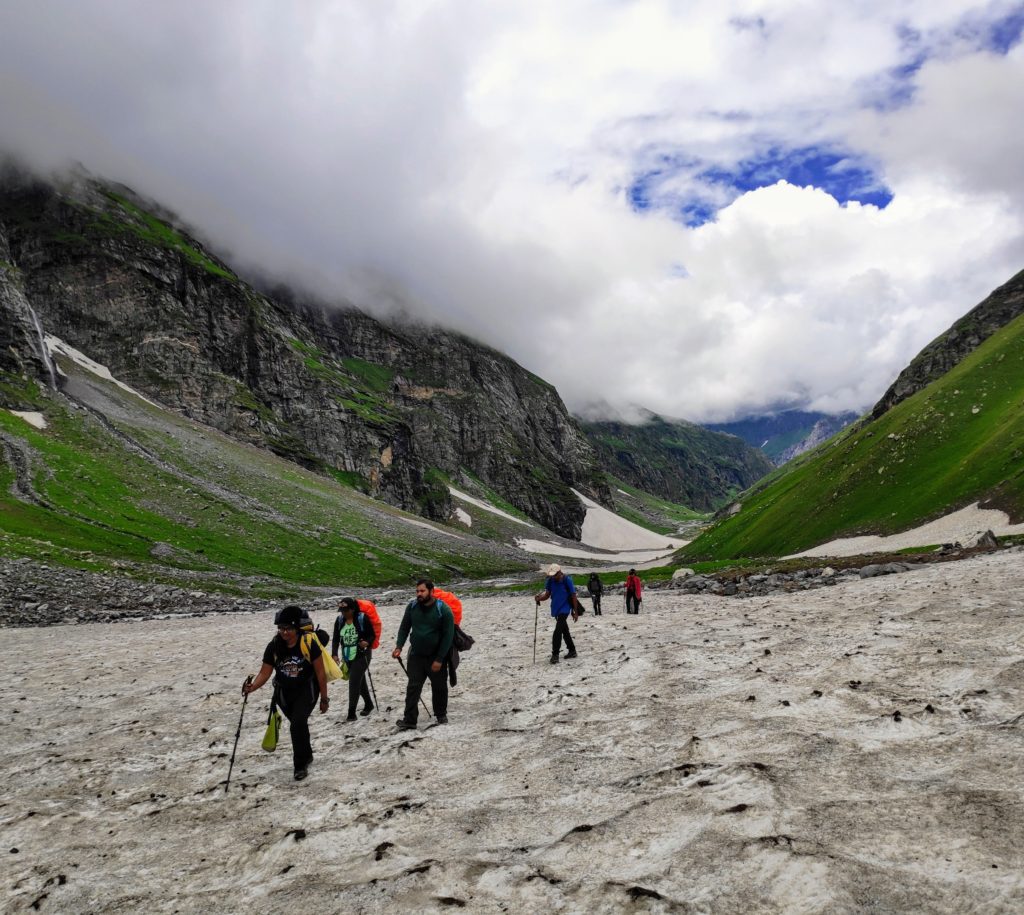 Trekkers climbing on a snow clad mountain route under a cloudy sky