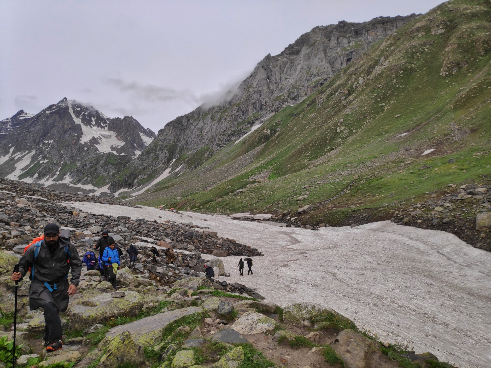 Trekkers crossing a river covered with ice in a mountainous setting